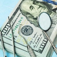 money and dental tools symbolizing cost of dental implants in Allen