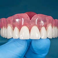 Denture for upper arch resting on gloved hand