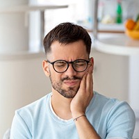 Man wearing pained expression, struggling with a toothache