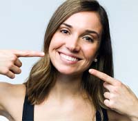 Woman pointing at teeth, happy she could afford dental implants
