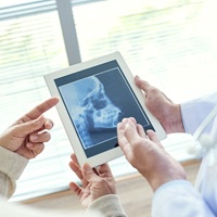 Two dental professionals examining and discussing patient’s jaw X-ray