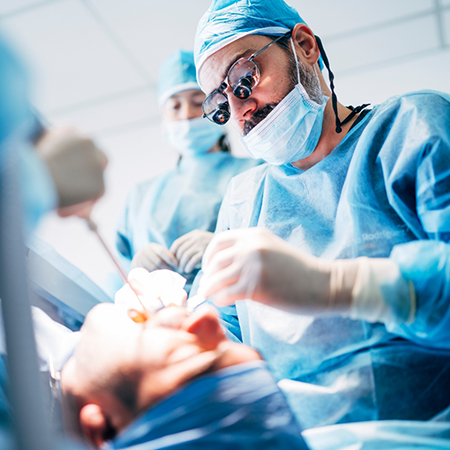 Dentist and team members performing wisdom tooth extractions on a patient
