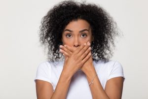 embarrassed young woman covering mouth with both hands