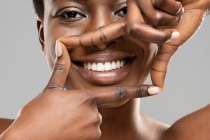 Woman using fingers to frame smile with dental implants in Allen