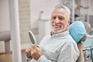 Happy senior man at dentist, using his dental insurance