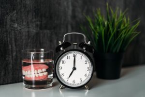 Dentures on bedside table, next to clock